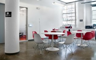 Tables and chairs near a kitchen space. 