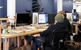 Two people sitting and looking at a computer screen. 