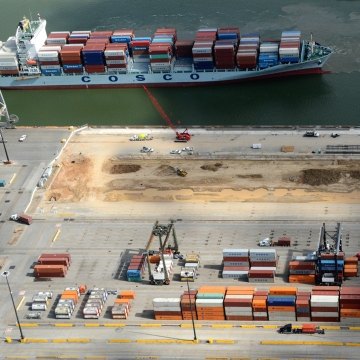 Aerial view of the site during construction with a ship on the water in the background