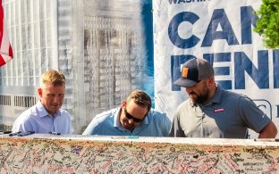 Three people signing a beam.