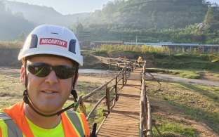 A person taking a selfie with a bridge in the background