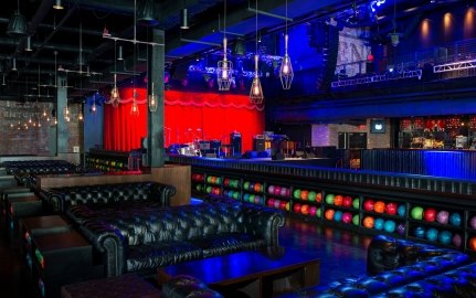 A bowling area with couches and shelves of neon-colored bowling balls.