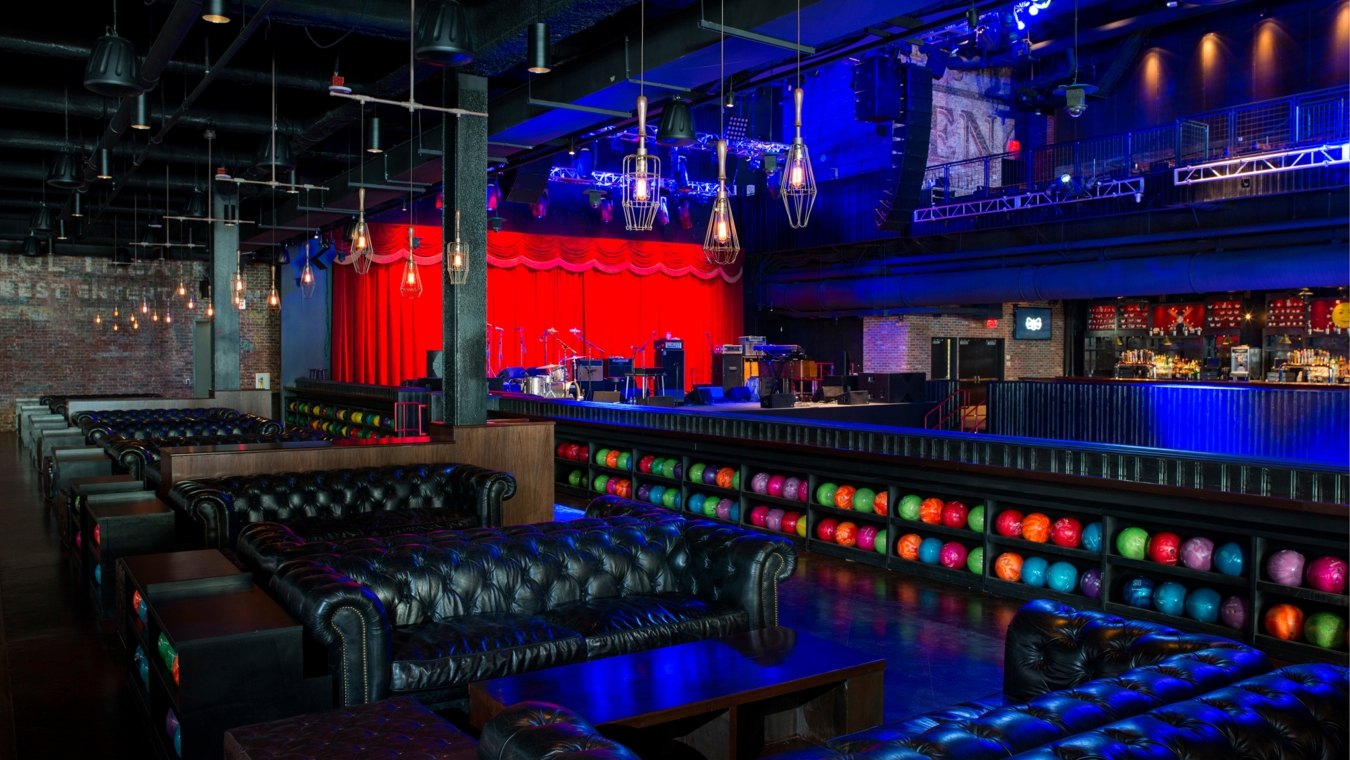 A bowling area with couches and shelves of neon-colored bowling balls.