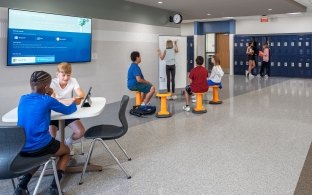 People sitting at tables and chairs in a hallway area