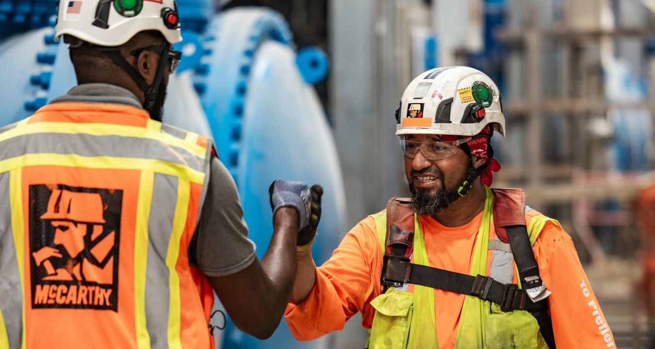 Two people fist-bumping on a jobsite. 