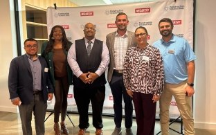 Group of people standing in front of a Construction Inclusion Week banner. 