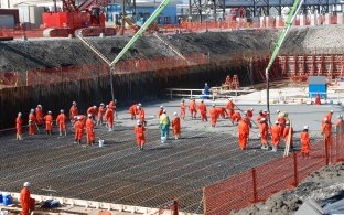 Outdoor image of workers in orange jumpsuits building