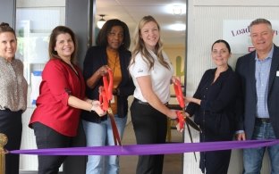 A group of people doing a ribbon cutting in front of the Homeward Bound facility.