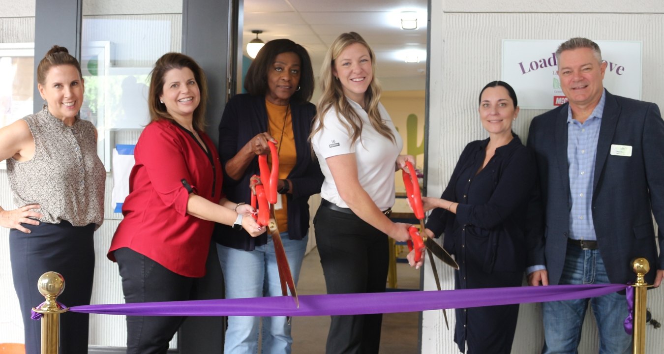 A group of people doing a ribbon cutting in front of the Homeward Bound facility.