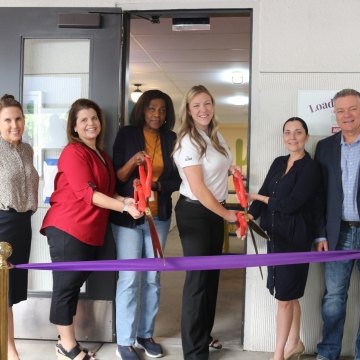 A group of people doing a ribbon cutting in front of the Homeward Bound facility.