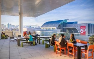 People sitting at tables and chairs in an outdoor seating area.