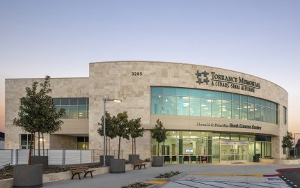 Entrance and front of the cancer center structure that features a blue sky and trees