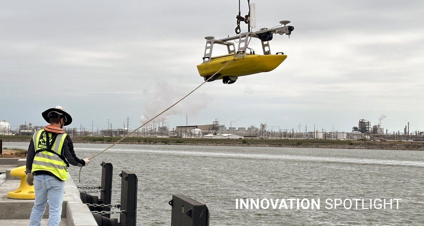 A person hoisting an unmanned survey vessel into the water