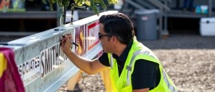 A man signing a beam