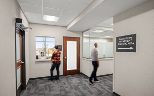 A person talking to someone else through a receptionist's window. 