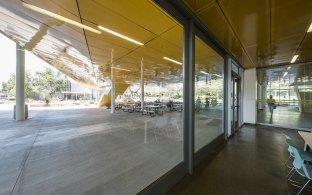 Indoor photo of a person walking and windows that show people sitting outside