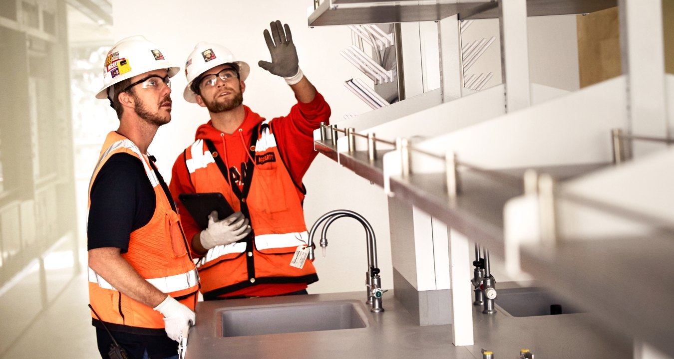 Two construction workers talking in a lab.