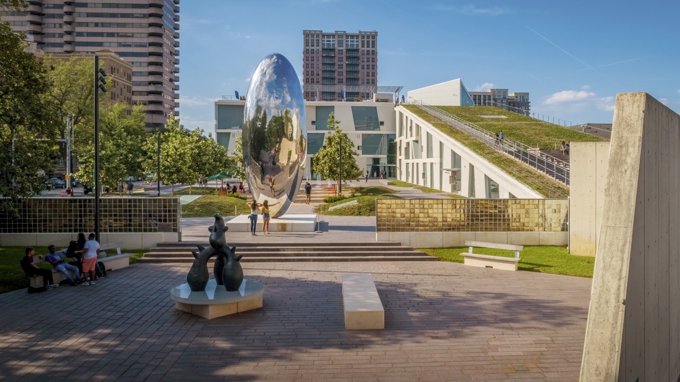 Outdoor image of the fine art park with people walking on concrete surrounded by grass