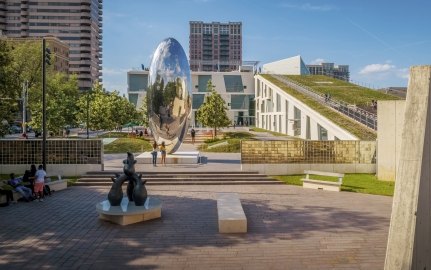 Outdoor image of the fine art park with people walking on concrete surrounded by grass