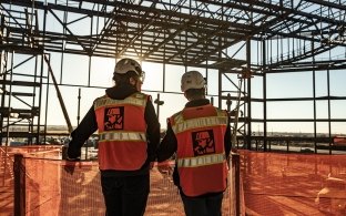 employees on a jobsite looking over a fence