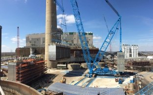 Outdoor image with blue skies and clouds with a blue crane moving building materials 