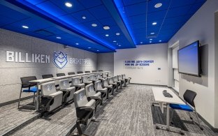 A classroom with two rows of theater-style seating and a TV at the front. 