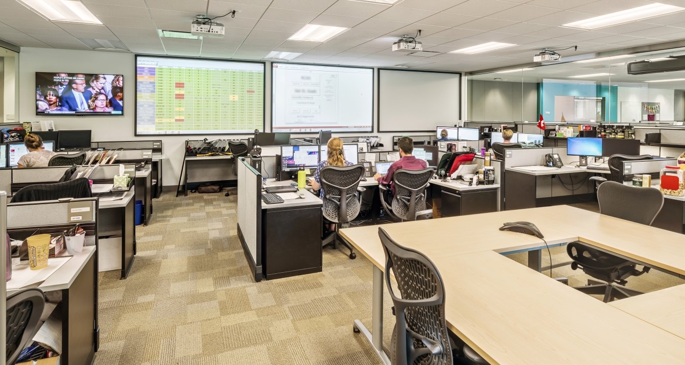 Indoor image of an office with cubes and people working