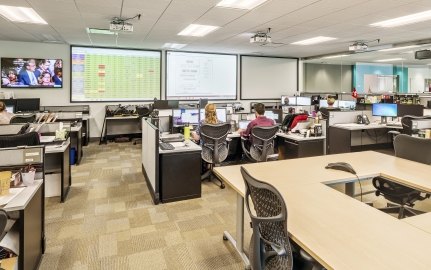 Indoor image of an office with cubes and people working