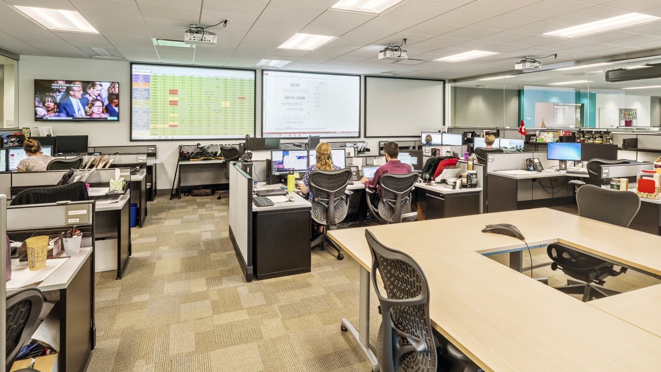 Indoor image of an office with cubes and people working