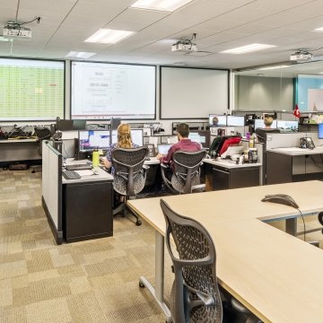 Indoor image of an office with cubes and people working