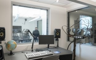 Soundboard, monitor, computer screen, and speakers in a studio setting.