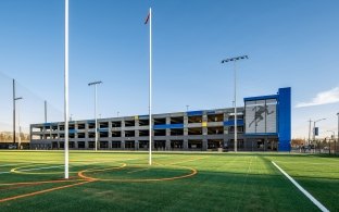 An athletic field with parking garage in the background.