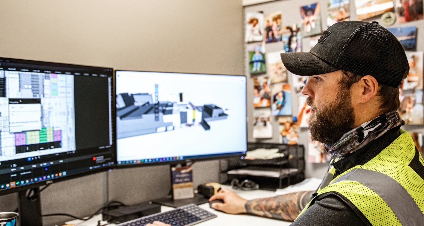 A person looking at two computer monitors