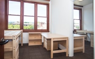 View of a dorm room with a bed and desk