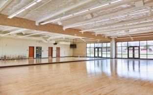 Large room with wood floors and mirrored wall