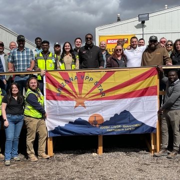 group of construction workers standing behind a flag