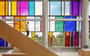 A man descends to the ground level of the VA hospital with stained glass windows in the background.