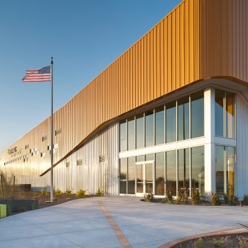 Outdoor image of the entrance with a flag pole and green seats